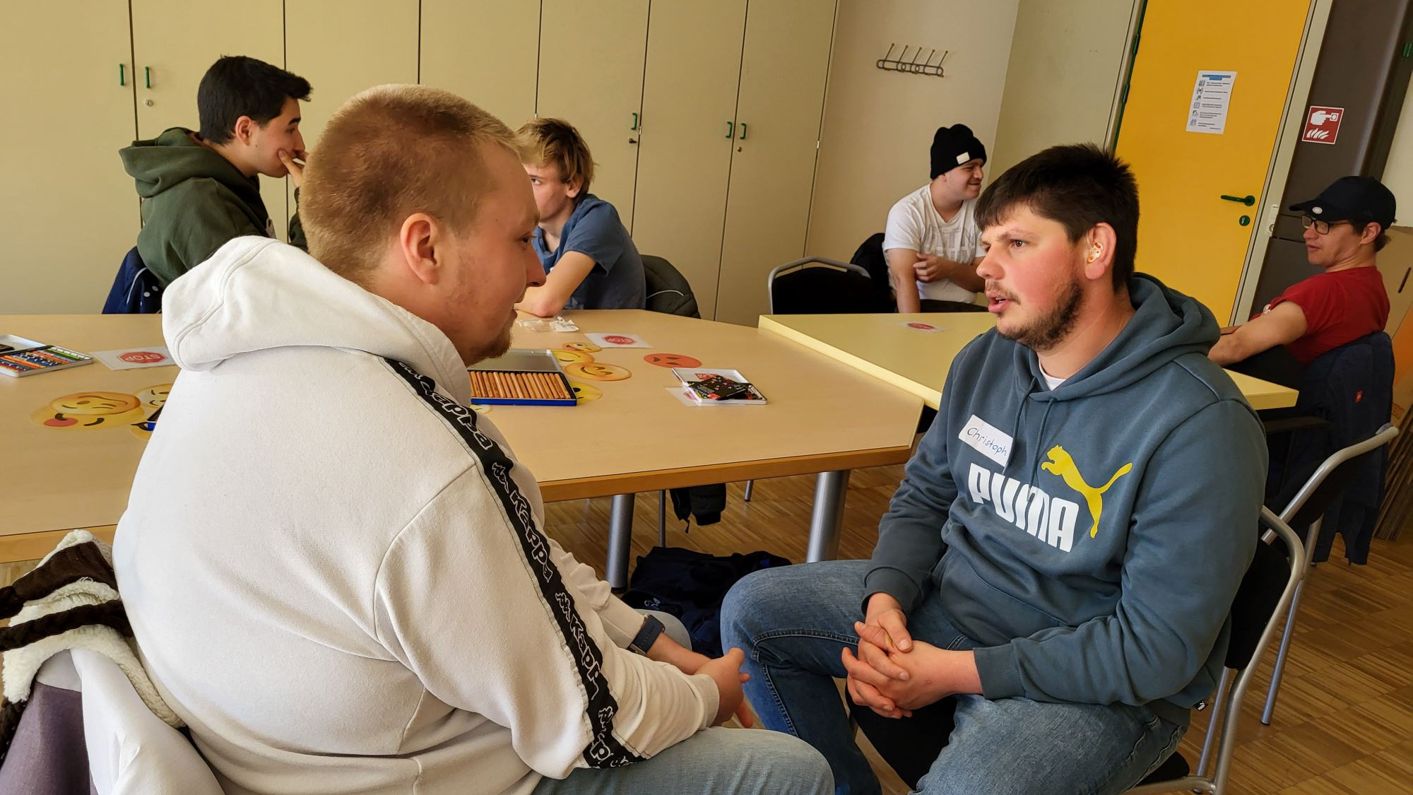 Mehrere Personen und Tische, jeweils zwei Personen miteinander im Gespräch